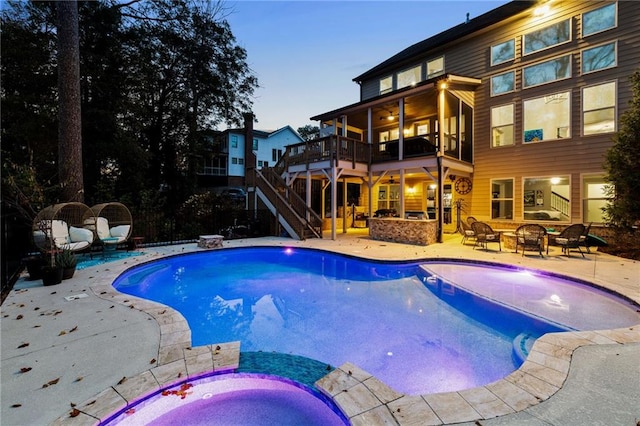 pool at dusk with a patio area, an outdoor fire pit, and an in ground hot tub