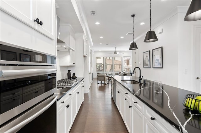 kitchen featuring hanging light fixtures, sink, stainless steel gas stovetop, white cabinetry, and dark hardwood / wood-style flooring