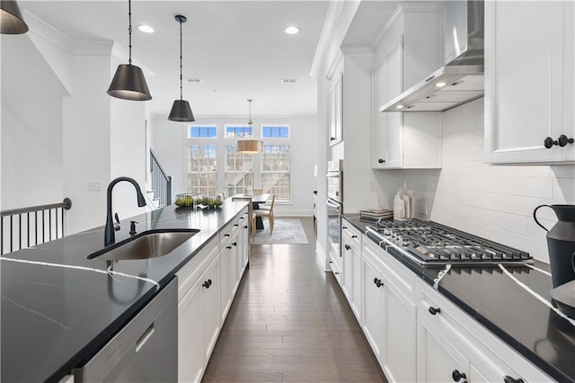 kitchen with wall chimney range hood, dark hardwood / wood-style floors, backsplash, sink, and pendant lighting