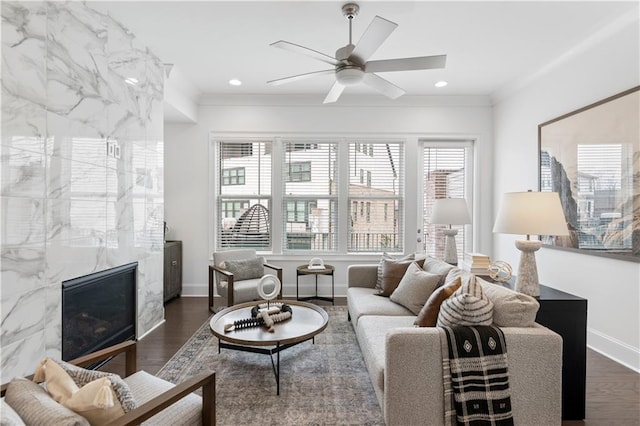 living room with crown molding, a fireplace, dark hardwood / wood-style floors, and ceiling fan