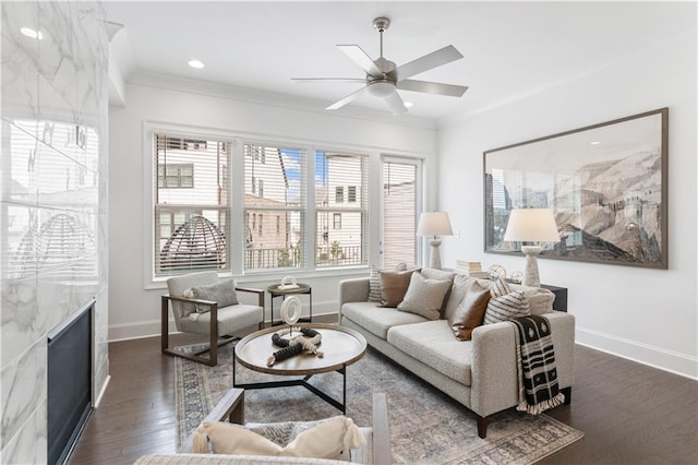 living room featuring ceiling fan, ornamental molding, dark hardwood / wood-style flooring, and a high end fireplace