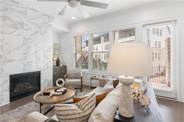 living room with crown molding, a healthy amount of sunlight, wood-type flooring, and a tile fireplace