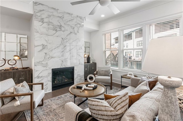 living room featuring ceiling fan, a high end fireplace, wood-type flooring, tile walls, and ornamental molding