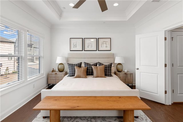 bedroom featuring dark wood-type flooring, ceiling fan, a tray ceiling, and multiple windows