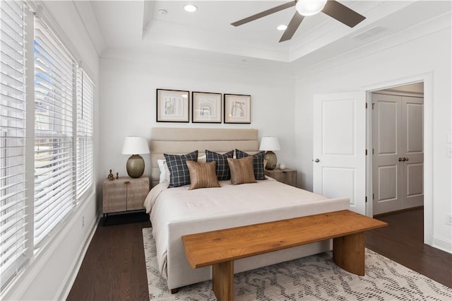 bedroom featuring dark wood-type flooring, a tray ceiling, and ceiling fan