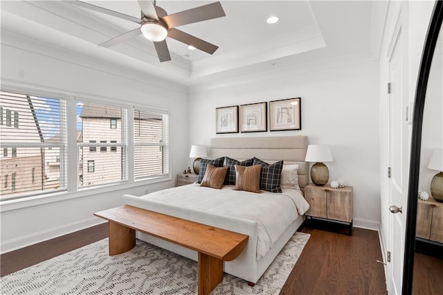 bedroom featuring dark wood-type flooring, a raised ceiling, and ceiling fan