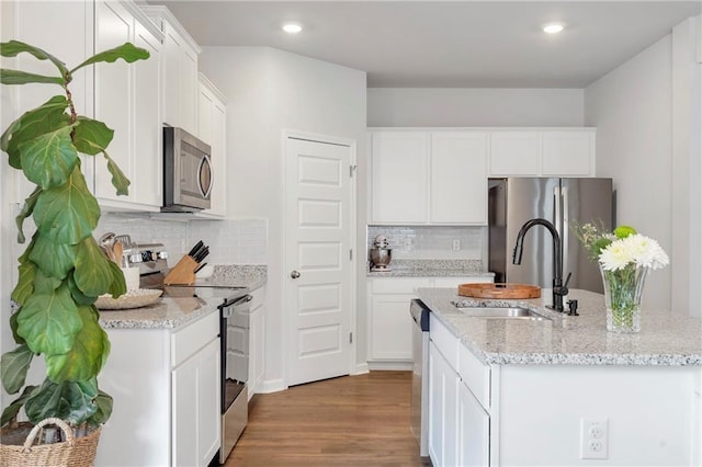 36 Mead Ct, Hoschton, GA 30548 - kitchen featuring appliances with stainless steel finishes, an island with sink, wood finished floors, white cabinets, and recessed lighting