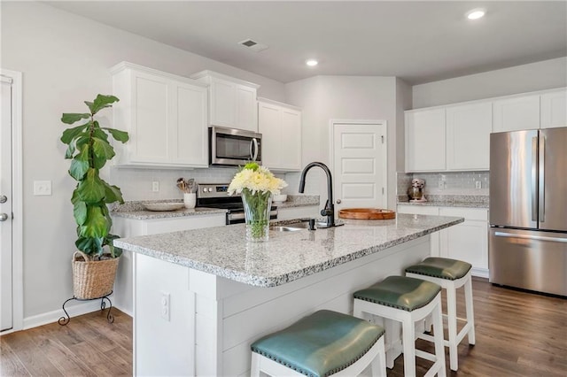 36 Mead Ct, Hoschton, GA 30548 - kitchen with stainless steel appliances, a kitchen breakfast bar, tasteful backsplash, white cabinetry, and recessed lighting