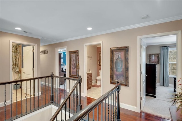 hall with crown molding, baseboards, an upstairs landing, and dark wood finished floors