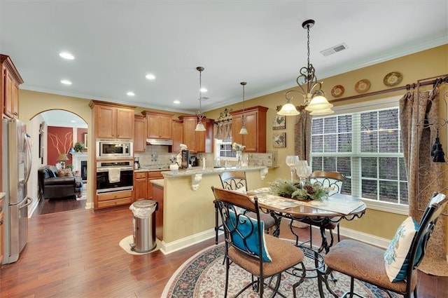dining space with arched walkways, visible vents, dark wood-style flooring, and ornamental molding