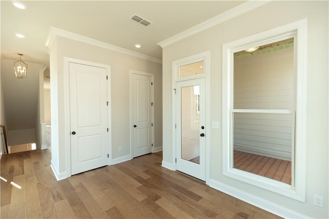 interior space with an inviting chandelier, crown molding, and hardwood / wood-style flooring