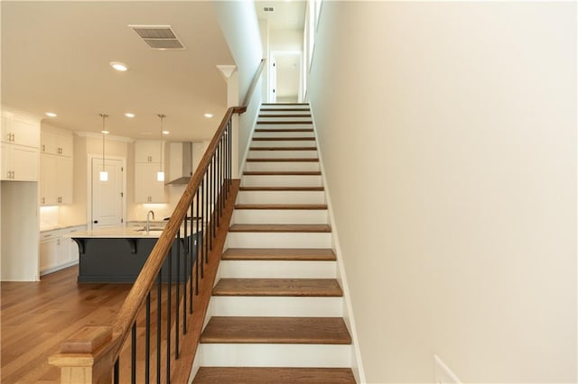 staircase with light hardwood / wood-style floors and sink