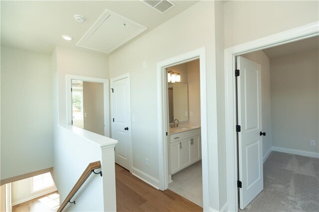 hall with sink and light colored carpet