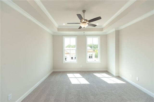 unfurnished room with ceiling fan, light colored carpet, and a tray ceiling