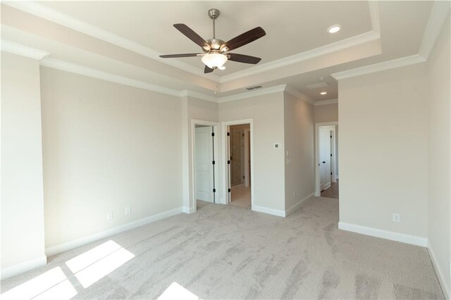 unfurnished bedroom featuring ceiling fan, crown molding, a tray ceiling, and light colored carpet