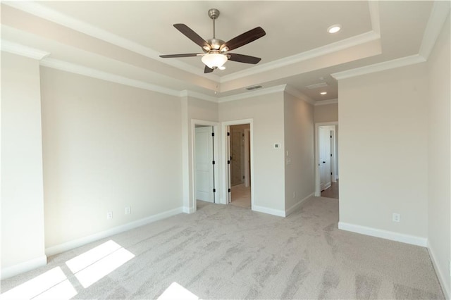 unfurnished bedroom featuring light carpet, a tray ceiling, ornamental molding, and ceiling fan