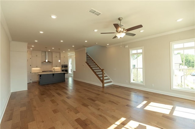 unfurnished living room featuring ceiling fan, ornamental molding, and light hardwood / wood-style floors