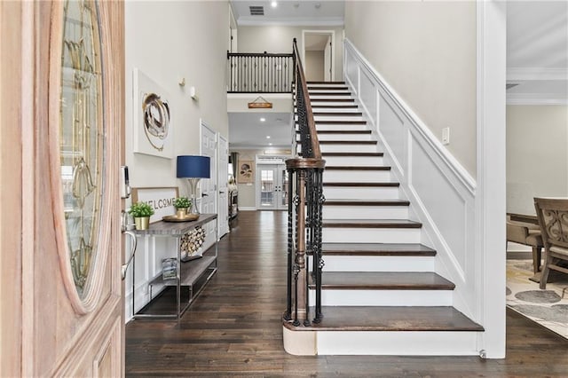 foyer featuring ornamental molding, dark hardwood / wood-style floors, and a towering ceiling