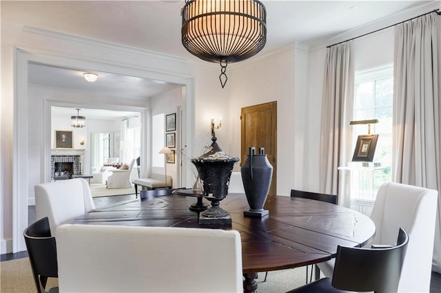 dining area with ornamental molding and a fireplace