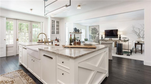 kitchen featuring light stone countertops, an island with sink, dark wood-style floors, and white cabinetry