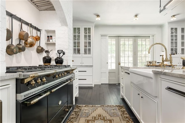 kitchen featuring white cabinetry, glass insert cabinets, double oven range, and a sink