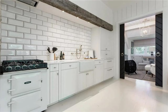 kitchen with beam ceiling, black gas cooktop, tasteful backsplash, white cabinetry, and light countertops