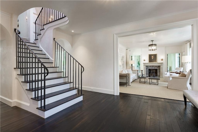 stairs featuring baseboards, a brick fireplace, hardwood / wood-style floors, and crown molding