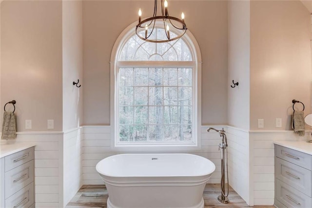 3000 The Springs Dr, Monroe, GA 30656 - bathroom with vanity, a wainscoted wall, a freestanding tub, a chandelier, and wood finished floors