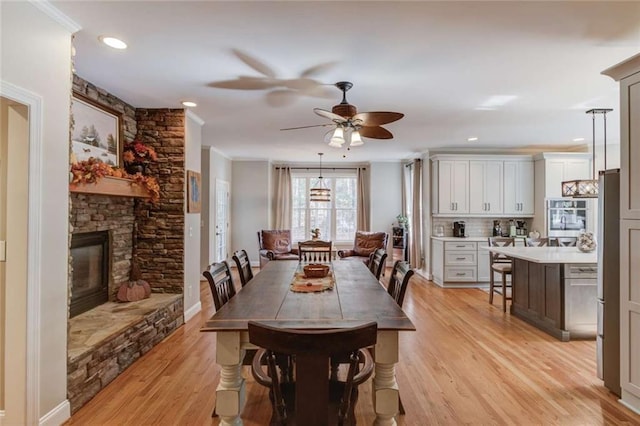 3000 The Springs Dr, Monroe, GA 30656 - dining area featuring light wood finished floors, a ceiling fan, crown molding, a stone fireplace, and recessed lighting