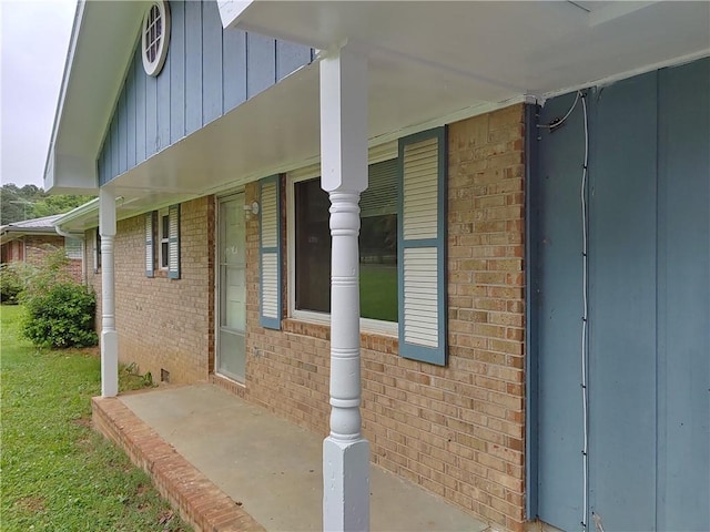 view of exterior entry with brick siding and covered porch