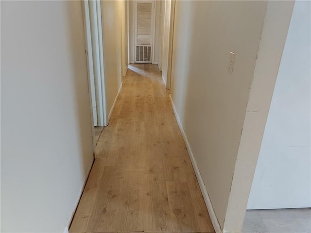 corridor featuring light wood-type flooring and baseboards