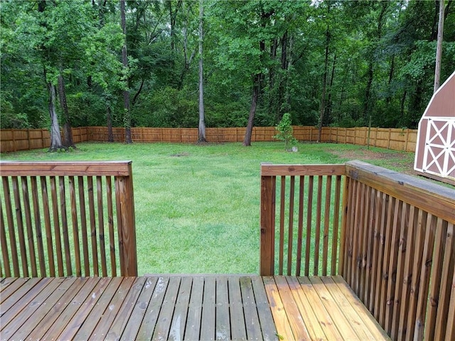 deck with an outbuilding, a lawn, a storage shed, and a fenced backyard