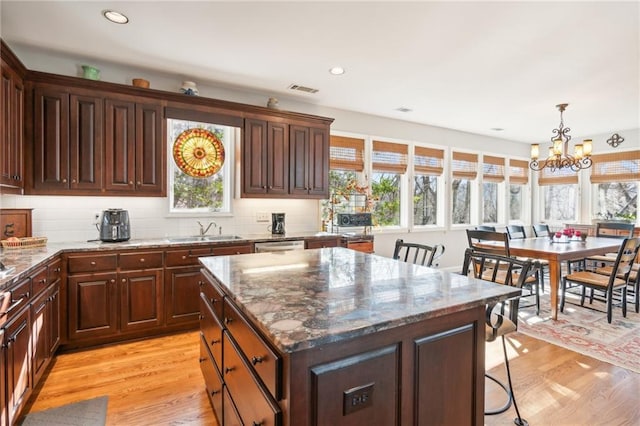 kitchen featuring sink, a center island, hanging light fixtures, an inviting chandelier, and light wood-type flooring