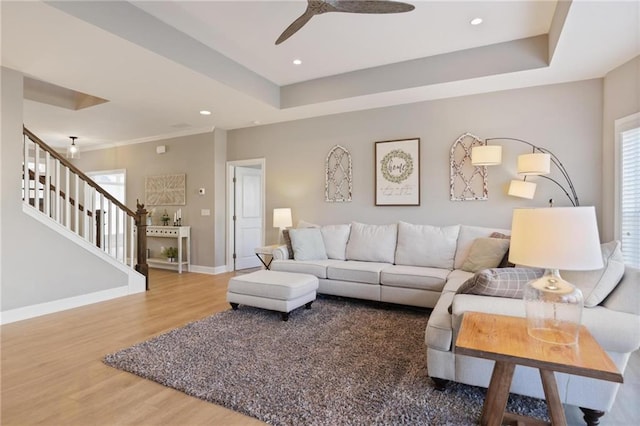 living area featuring baseboards, a raised ceiling, wood finished floors, and stairs