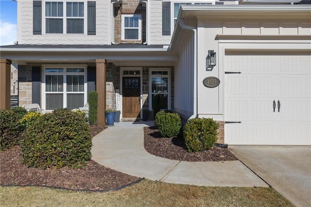 doorway to property featuring a garage, stone siding, and driveway