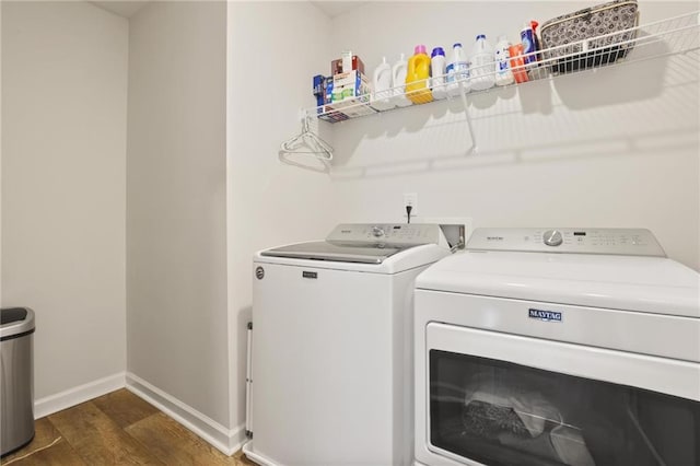 clothes washing area featuring baseboards, dark wood-style floors, laundry area, and washer and clothes dryer