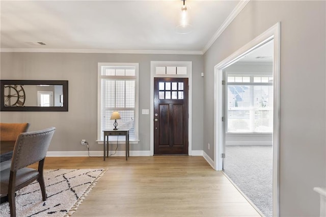 foyer entrance featuring visible vents, baseboards, light wood-style floors, and crown molding