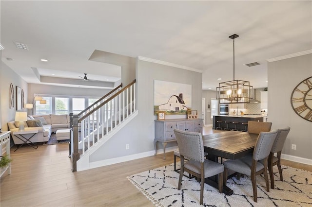 dining space featuring visible vents, baseboards, ornamental molding, and light wood finished floors