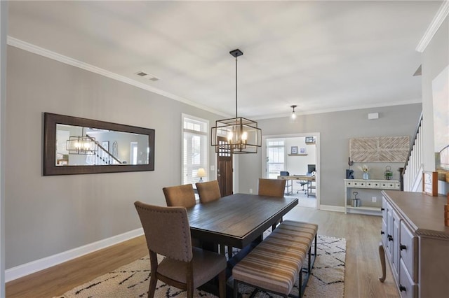 dining space with a notable chandelier, light wood-style flooring, baseboards, and visible vents