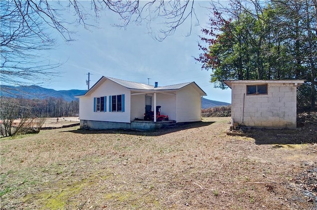 back of house with metal roof, an outdoor structure, a shed, and a mountain view