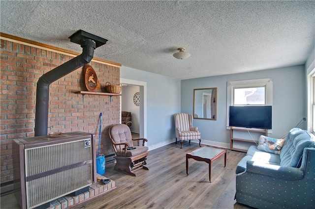 living area with a wood stove, a textured ceiling, baseboards, and wood finished floors