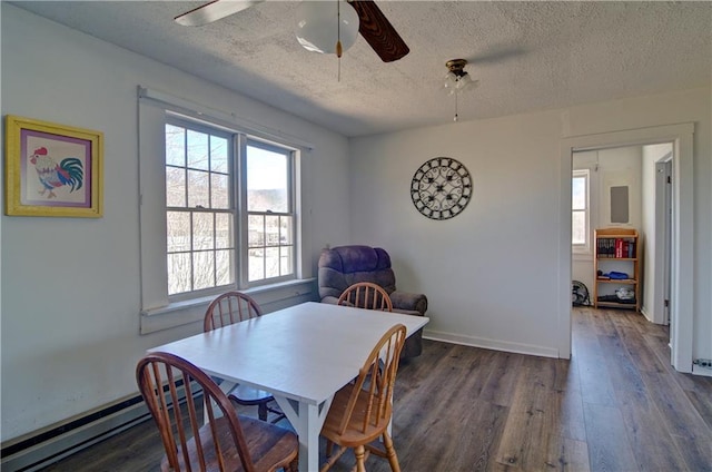 dining area with a textured ceiling, a baseboard heating unit, wood finished floors, a ceiling fan, and baseboards