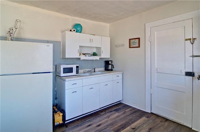 kitchen featuring white appliances, dark wood finished floors, white cabinets, light countertops, and a sink