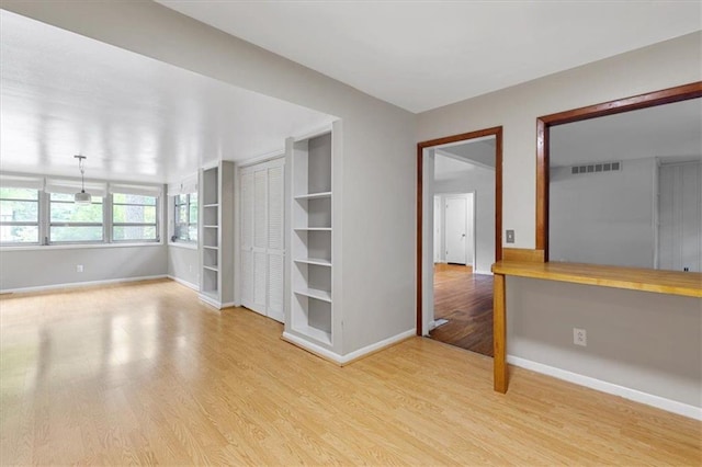 spare room featuring built in desk and light hardwood / wood-style flooring