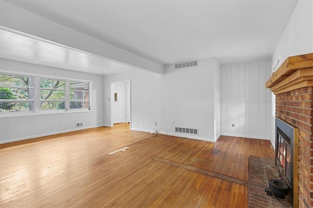 unfurnished living room with hardwood / wood-style flooring and a brick fireplace