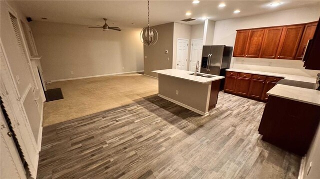 kitchen with pendant lighting, ceiling fan, light hardwood / wood-style floors, an island with sink, and stainless steel fridge with ice dispenser