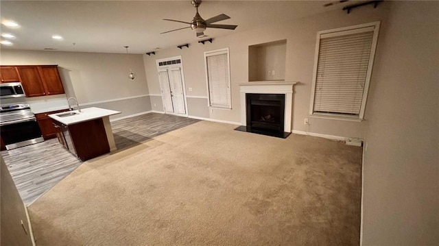 kitchen featuring sink, ceiling fan, appliances with stainless steel finishes, hanging light fixtures, and carpet floors