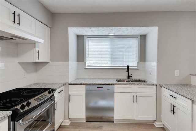 kitchen with light stone counters, sink, white cabinetry, and stainless steel appliances