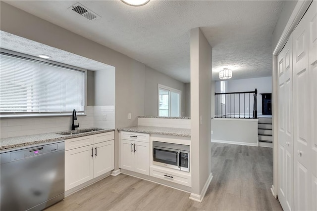 kitchen featuring white cabinets, stainless steel appliances, a textured ceiling, and light hardwood / wood-style floors