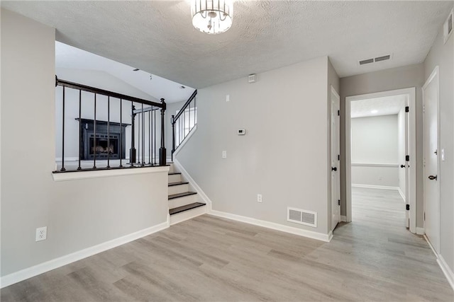 interior space with a textured ceiling, hardwood / wood-style flooring, and vaulted ceiling